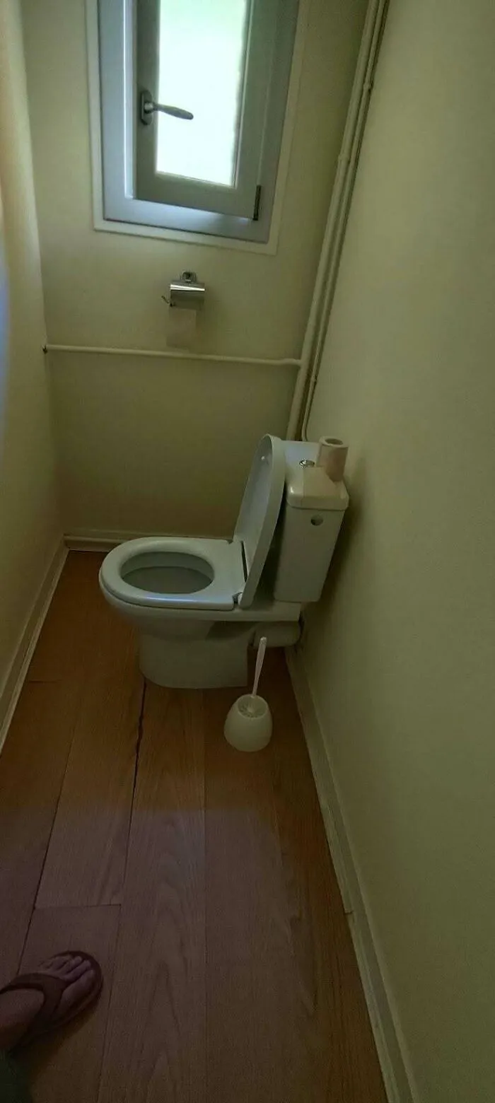 A poorly installed toilet blocking a bathroom doorway, showing a funny construction fail.