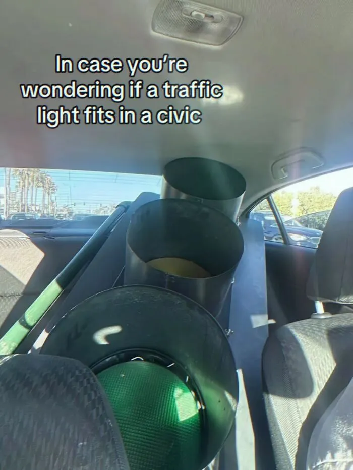 Hilarious real life meme displaying a full-sized traffic light stuffed into the backseat of a Honda Civic.