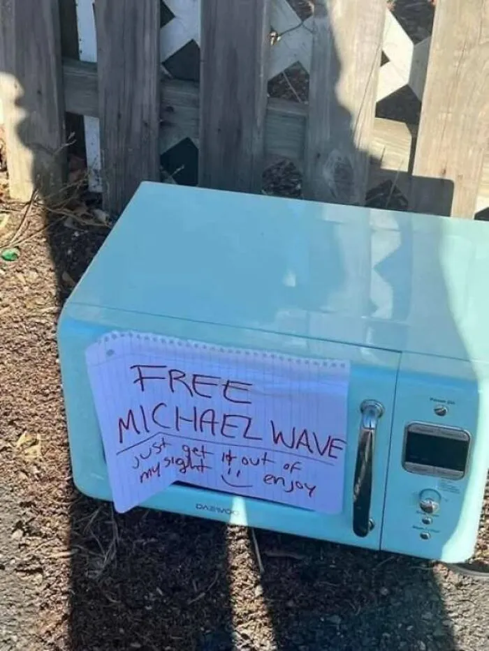 A blue microwave on the street with a sign that says Free Michael Wave
