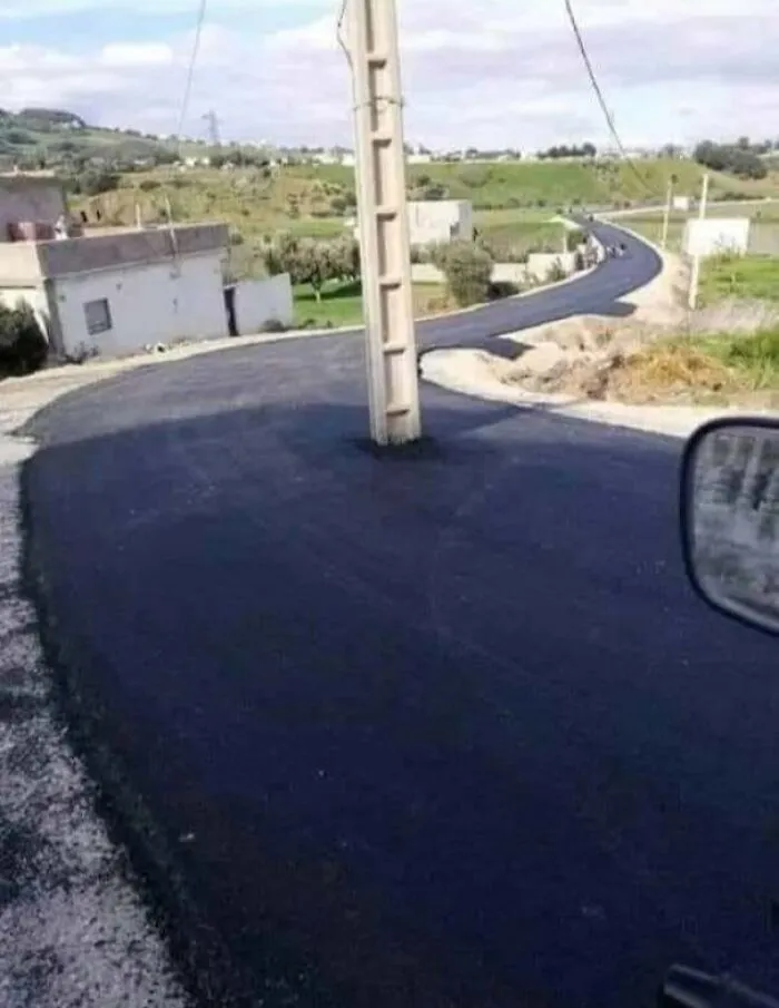 Utility pole placed directly in the middle of a newly paved road as a construction fail.