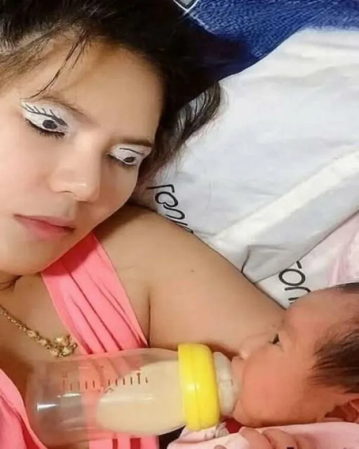 Strange and funny pics of a mother with fake open eyes painted on eyelids bottle feeding a baby.
