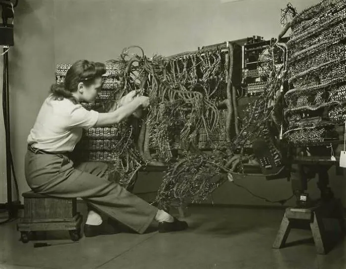 Woman working on wiring of early computer vintage technology