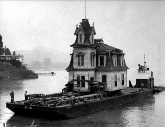 Vintage photo of a house being transported on a barge on the water