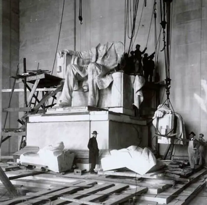 Black and white image of Lincoln Memorial statue under construction with workers around