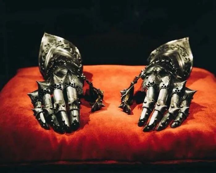 Medieval blackened gauntlets displayed on a red cushion