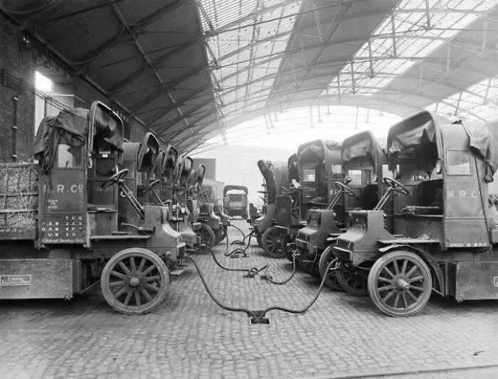 Row of early electric delivery trucks plugged in inside a warehouse