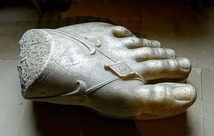 Ancient sculpted marble foot with detailed sandal design on display