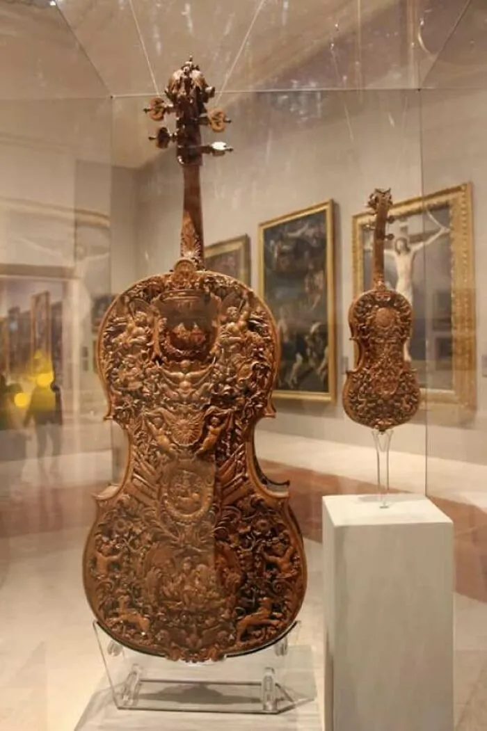 Intricately carved wooden violins in a museum display case