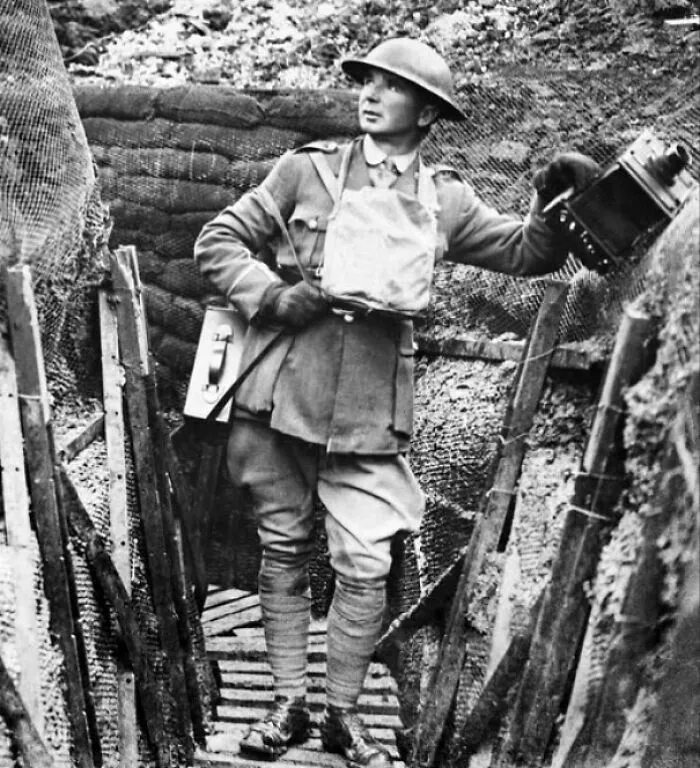 Black and white photo of a WWI soldier with vintage camera in trench