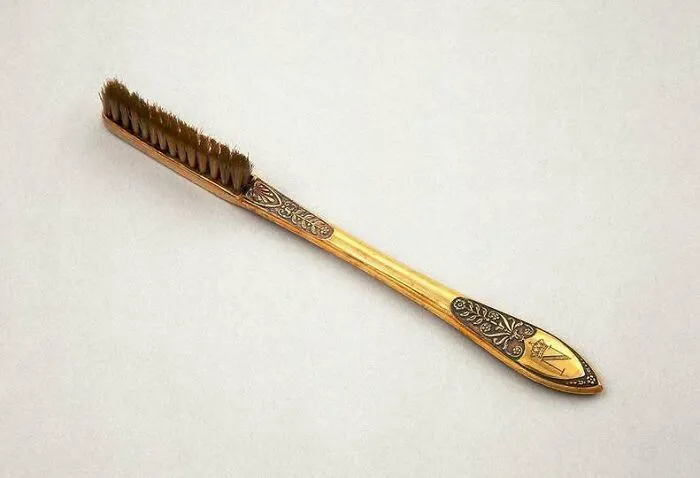 Vintage gold toothbrush with ornate floral design historic dental tool