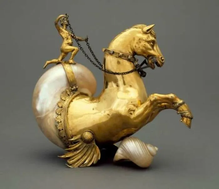 Golden horse sculpture with seashell and small figure holding reins history artifact