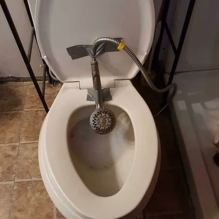 Improvised Slavic Engineering showing a shower head duct-taped inside a toilet bowl as a bidet.