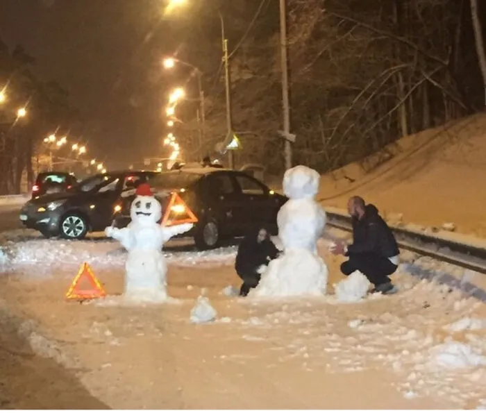 Funny Slavic Engineering example with people building snowmen on a road next to parked cars.