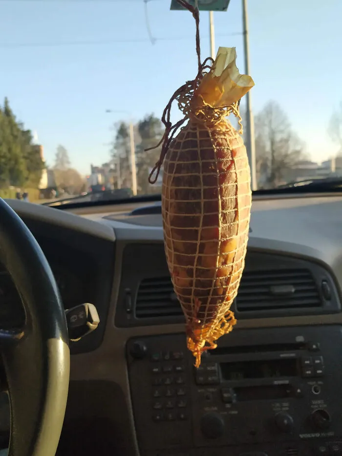 Sausage link hanging from a car rearview mirror as a unique air freshener, an example of Slavic engineering.