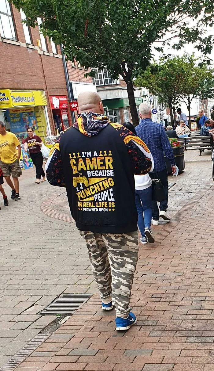 Man wearing hoodie saying I'm a gamer because punching people in real life is frowned upon walking in town