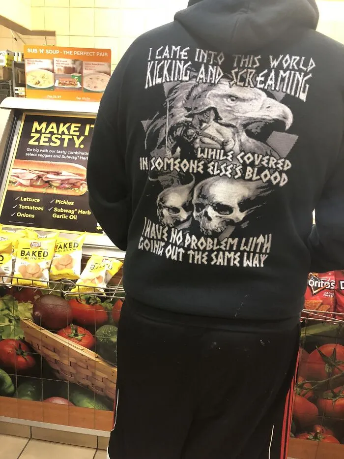 Person wearing hoodie with aggressive text about coming into world kicking and screaming