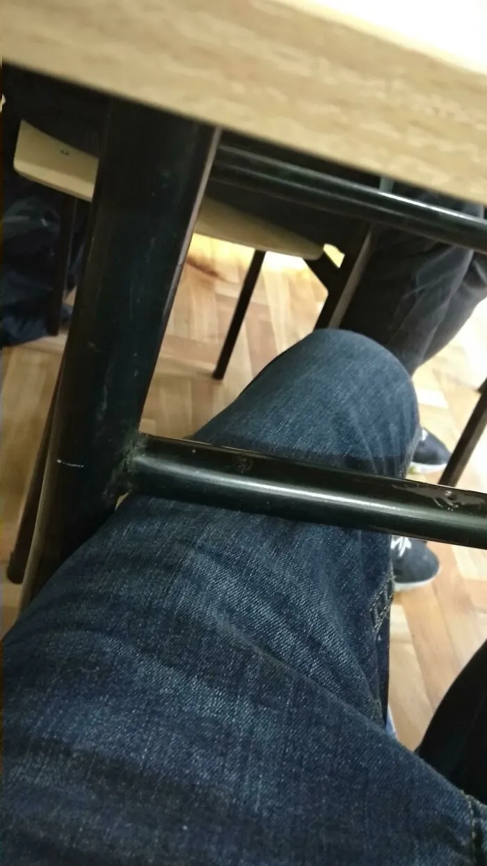 Ridiculous design of table bar hitting person's knee, showing poor ergonomic design choice