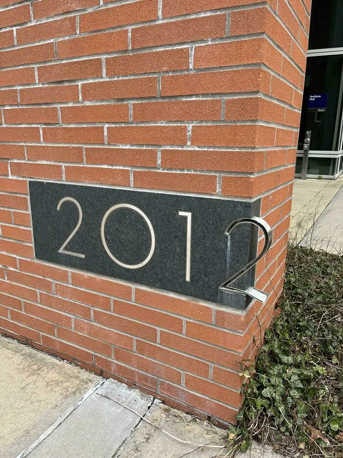 Building number sign with 2012 where number 2 protrudes oddly from wall