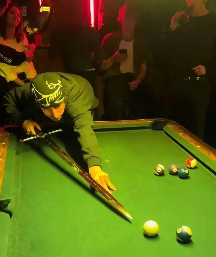 Hilarious pics of a young man using a sword instead of a cue stick to line up a pool shot