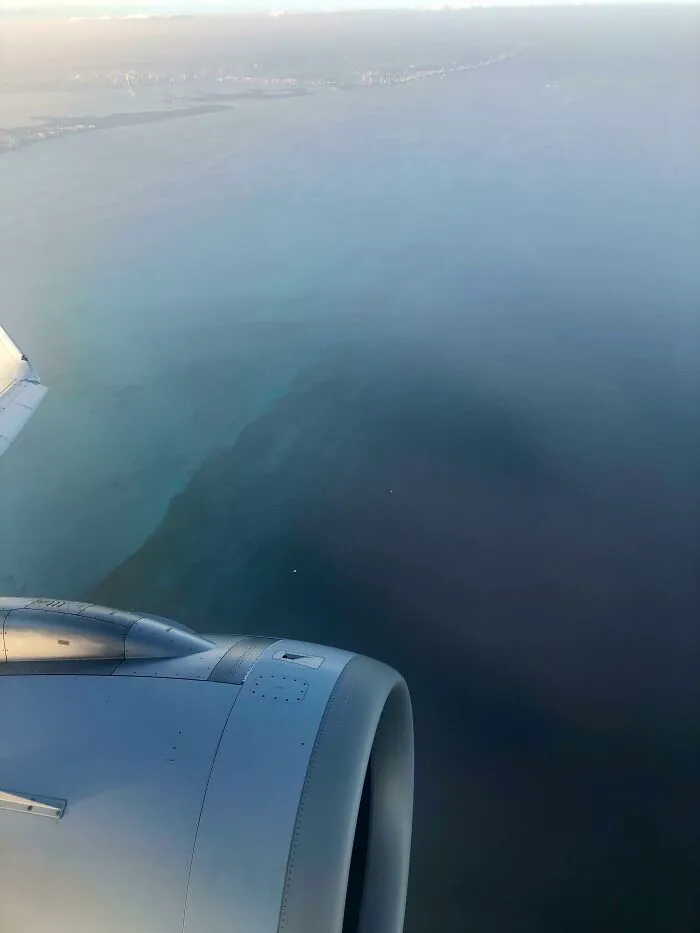 Aerial view of deep water ocean from airplane window with visible coastline