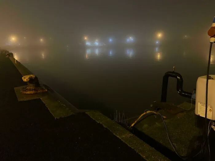 Foggy harbor at night with eerie reflections over deep water