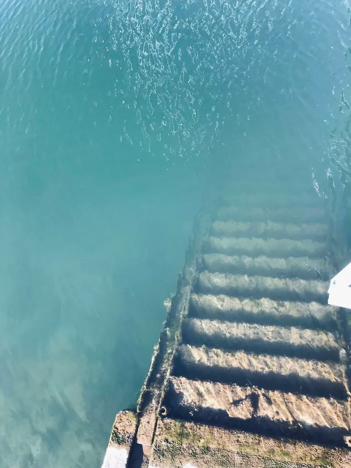 Underwater stairs covered in algae descending into clear deep water