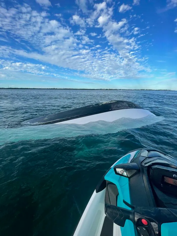 Upside down boat visible in deep-water sea near jet ski