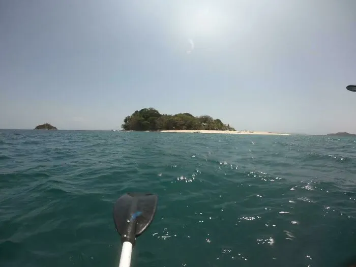 View of small forested island from kayak on deep ocean water
