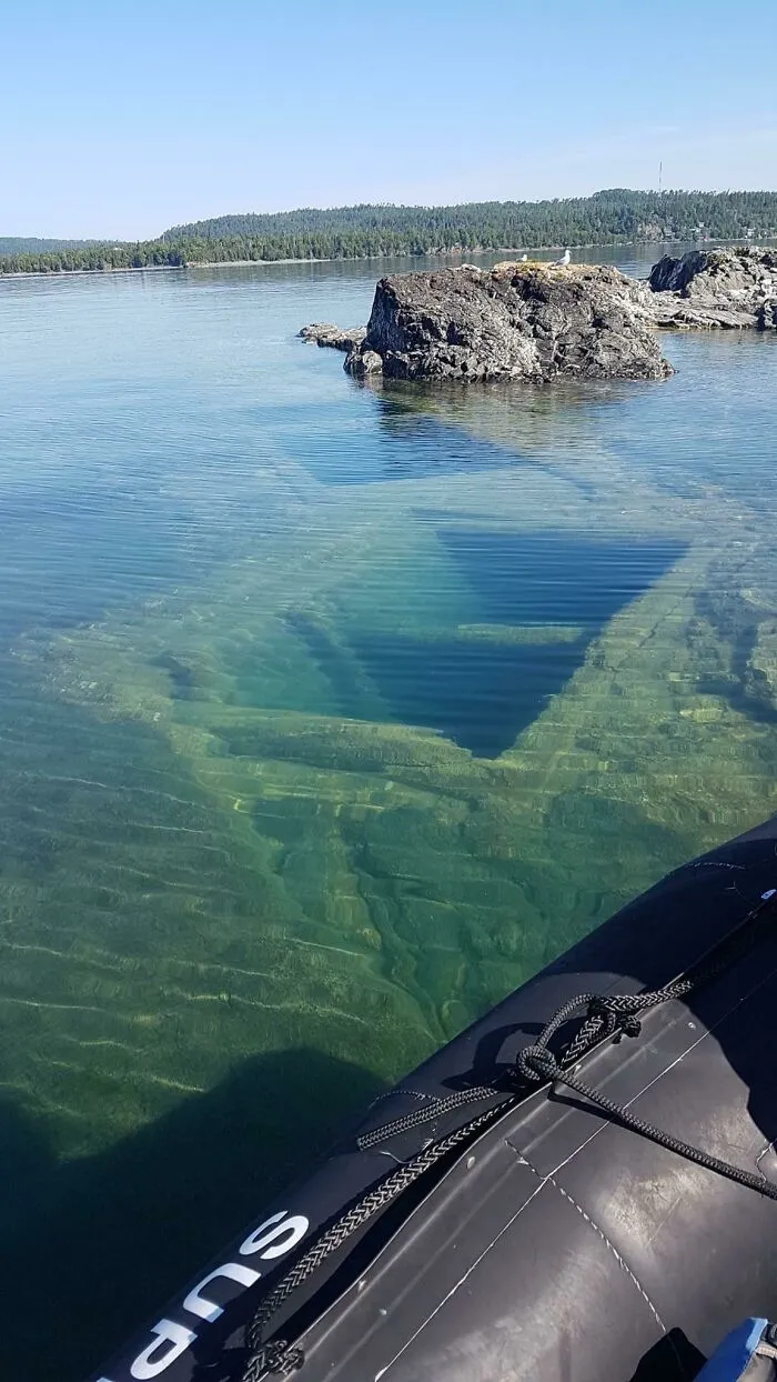 Underwater shipwreck partially visible near rocky shoreline