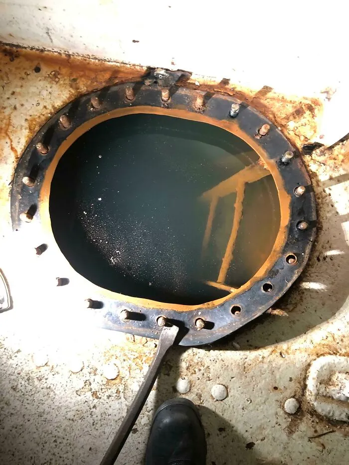 Rusty metal hatch opening to reveal deep-water tank inside