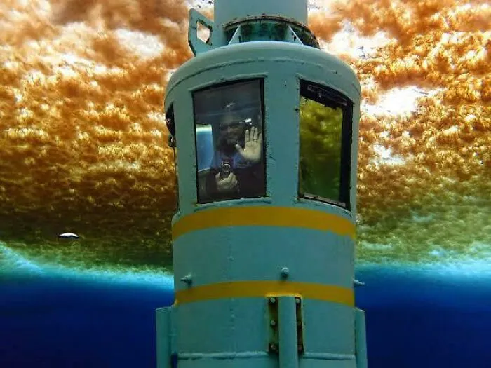 Underwater view of a person inside a small submarine in deep water