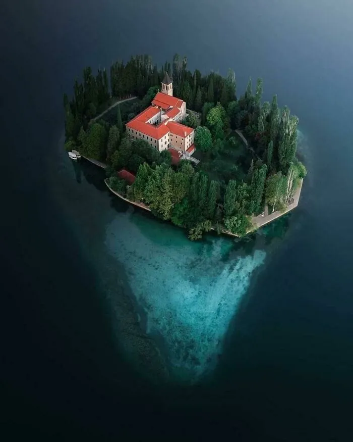 Aerial view of island with building surrounded by deep water