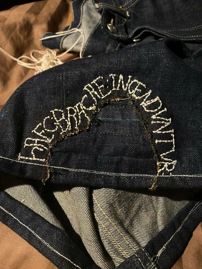 Custom embroidered lettering on denim clothing showing creativity to repair items and save money.