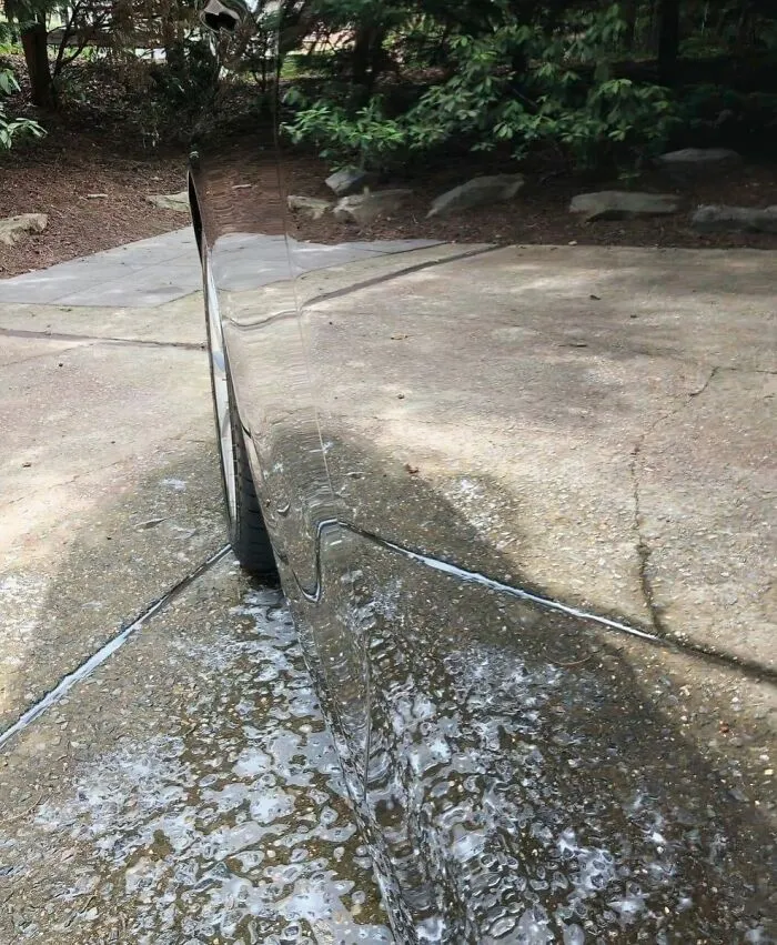 A high shine car reflecting the driveway, creating a mind trick optical illusion image.