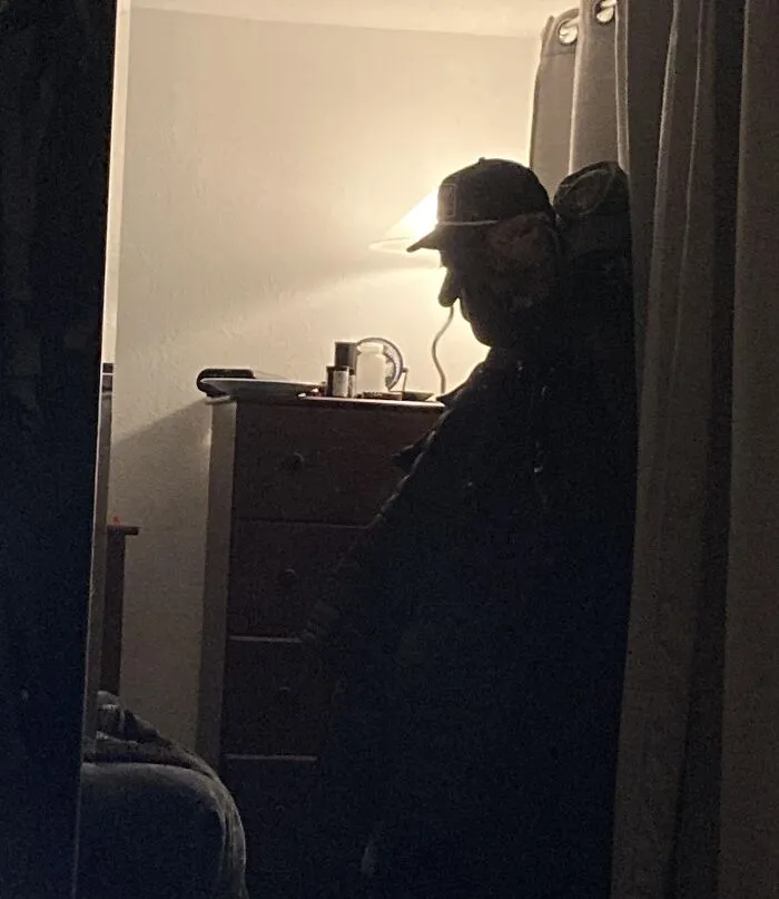 A shadow cast by curtains creating an optical illusion of a man in a hat