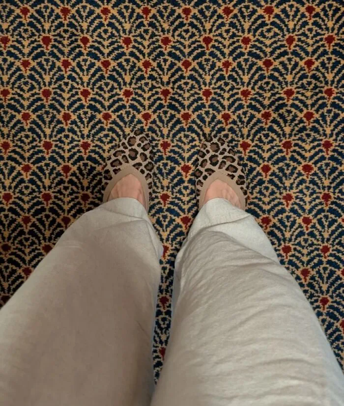Person wearing leopard print shoes matching patterned carpet, making eyes play tricks.