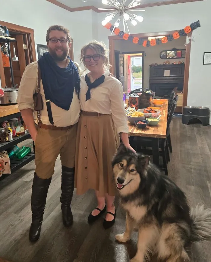A man and woman posing in safari themed cool Halloween couples costumes indoors with their large fluffy dog