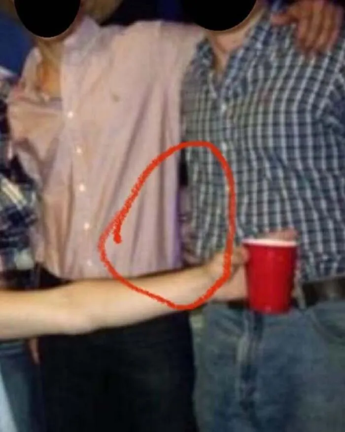 Optical illusion real-life photo showing a detached arm holding a drink like a horror movie scene