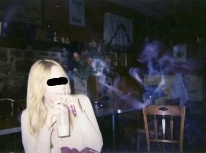 Real-life photo of a woman drinking with mysterious smoke patterns floating like a horror movie scene.