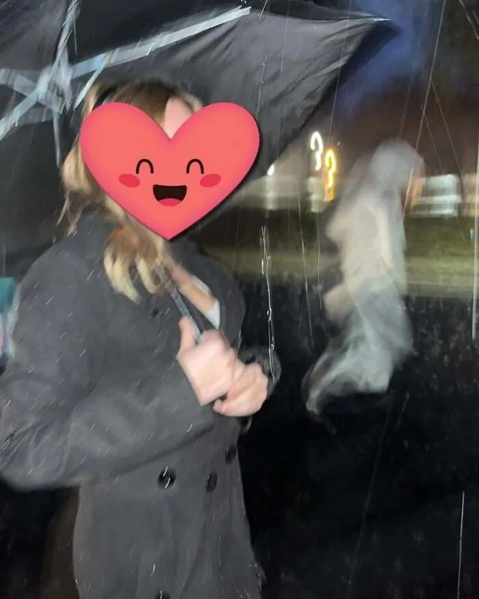 Woman holding an umbrella with a blurry ghost-like figure behind her in a real-life horror movie style photo