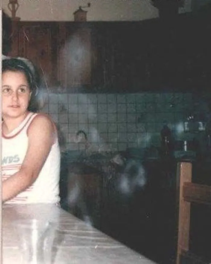 Eerie ghostly mist appearing near a child in a kitchen, like a scene from a horror movie.