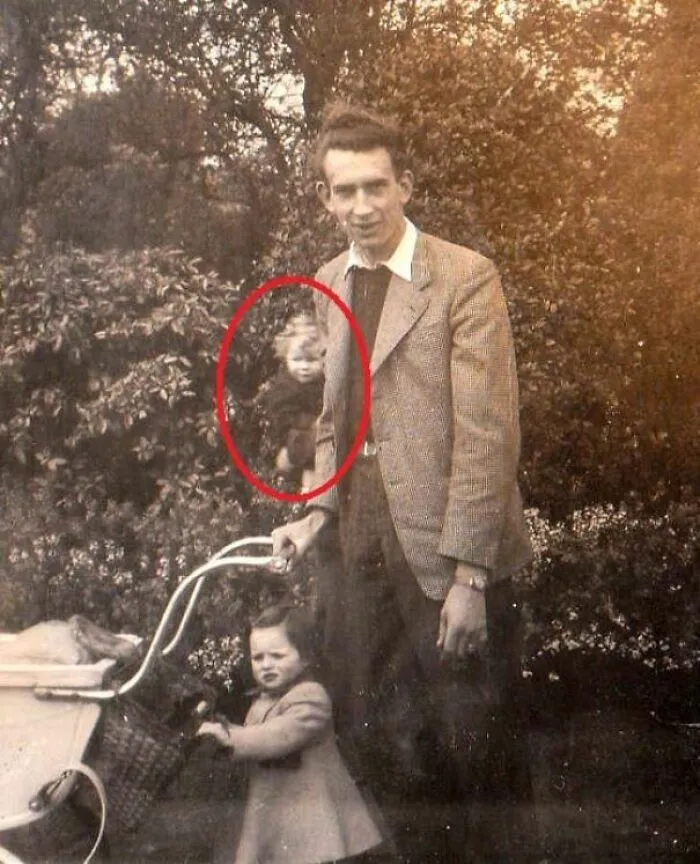 Eerie ghostly face floating near a family outdoor portrait in real-life photos like a horror movie
