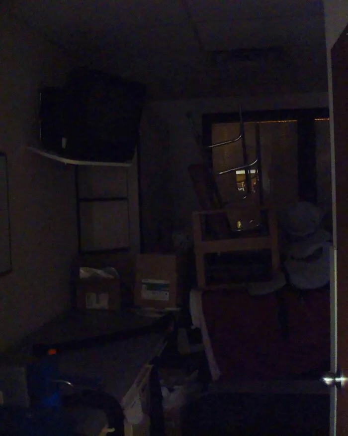 A dark storage room with stacked furniture looking like a creepy scene from a horror movie.