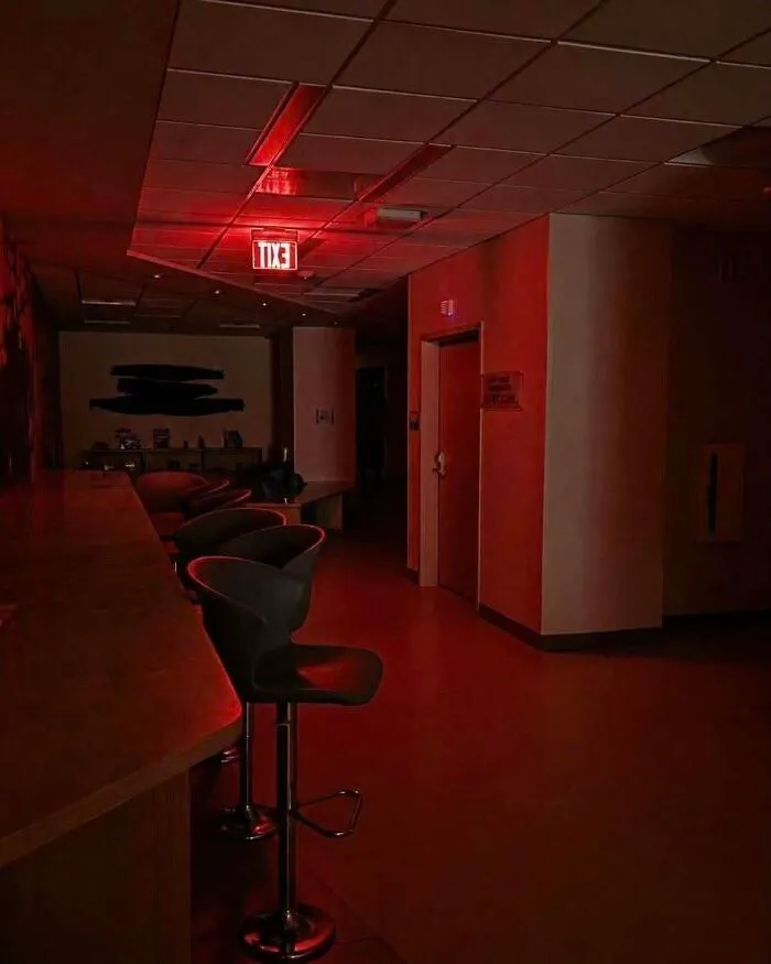 A dim hallway lit with eerie red lights in a scene resembling real-life photos from a horror movie.
