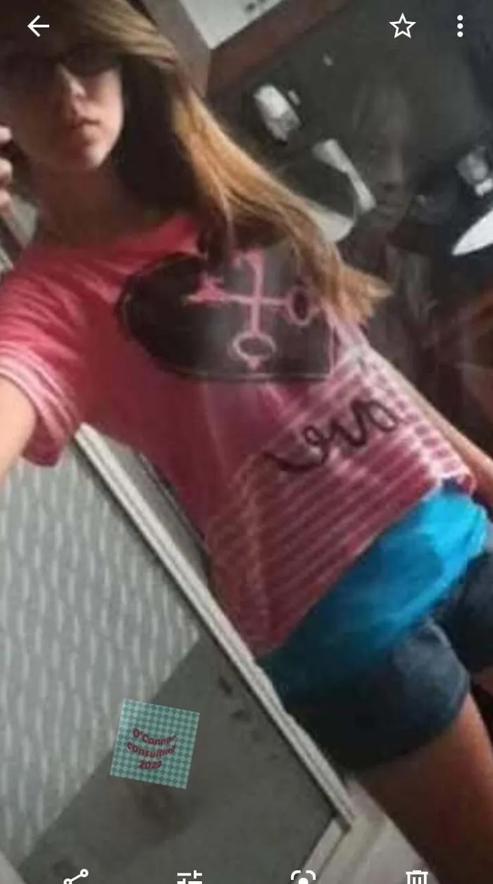 Girl taking a selfie with a creepy faint reflection behind her, giving horror movie vibes