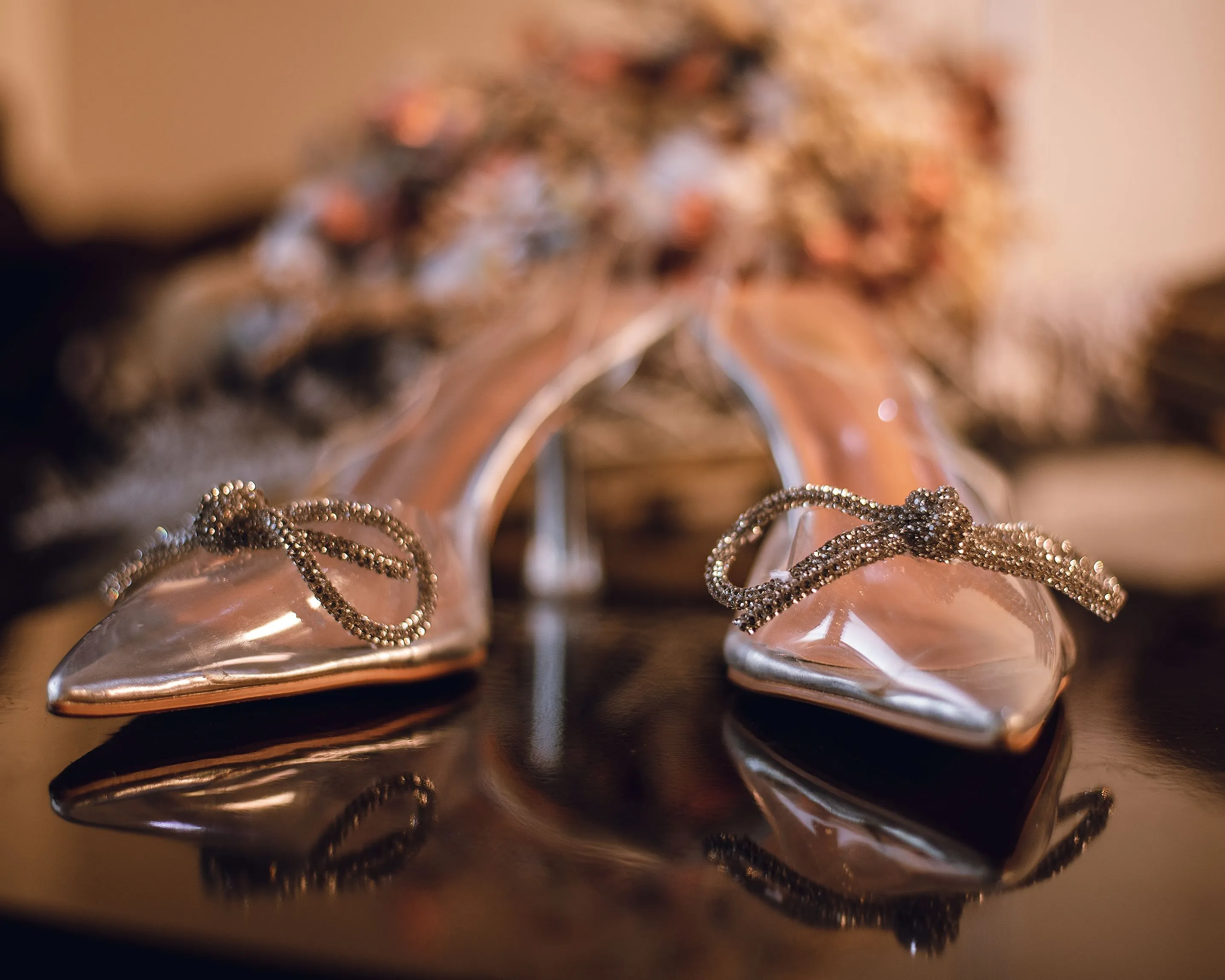 Pair of elegant clear high heels with sparkling bow details, reminiscent of a glass slipper.
