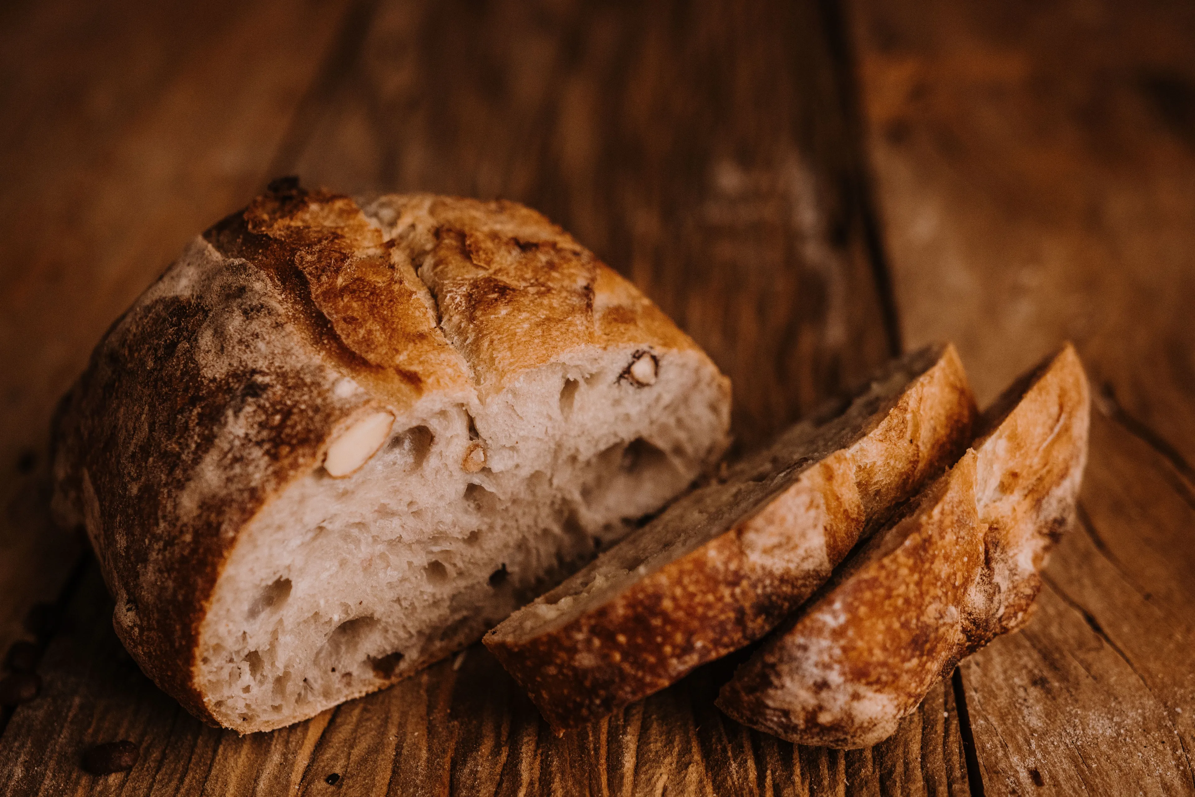 Freshly baked loaf of artisanal bread sliced on a rustic wooden table