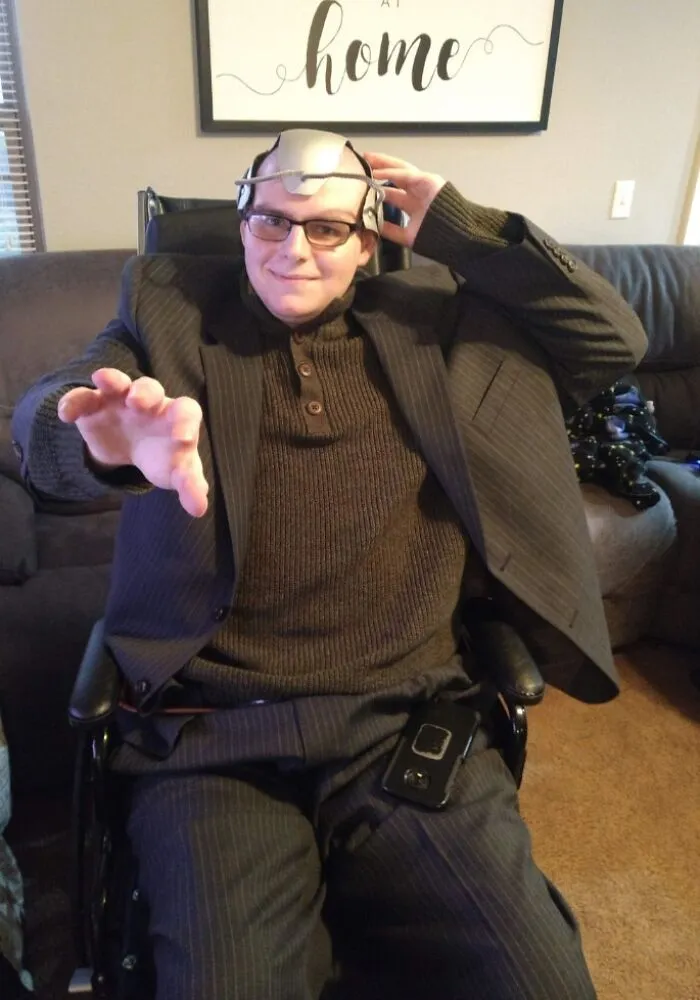 Man in suit and Cerebro helmet in wheelchair posing as Professor X, showing creative people with disabilities