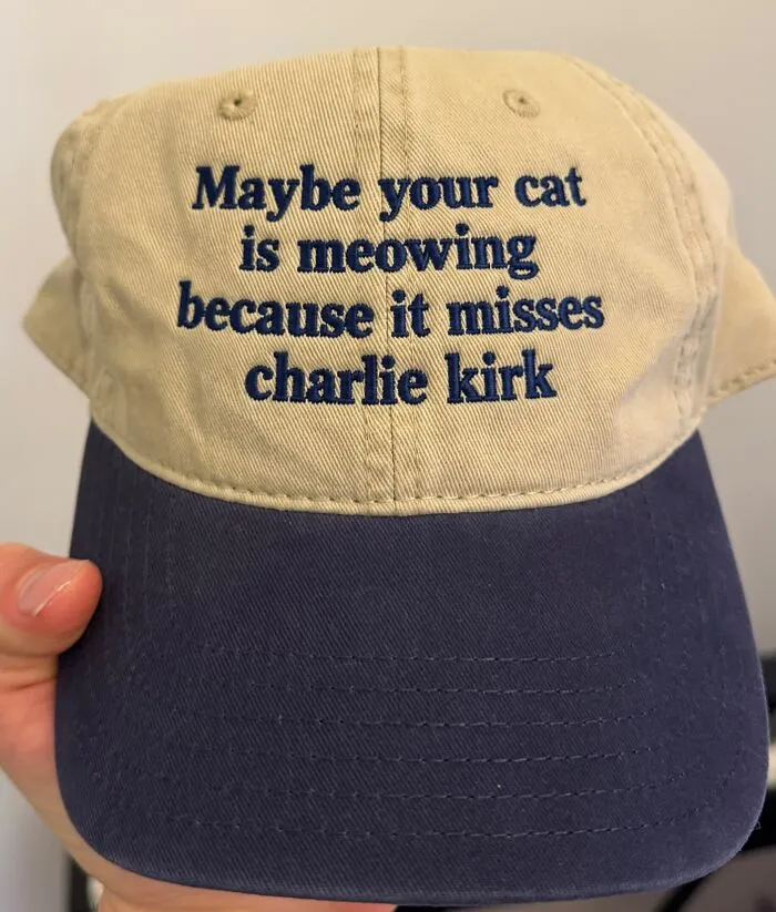 Beige and blue hat featuring embroidered text asking if your cat misses Charlie Kirk.