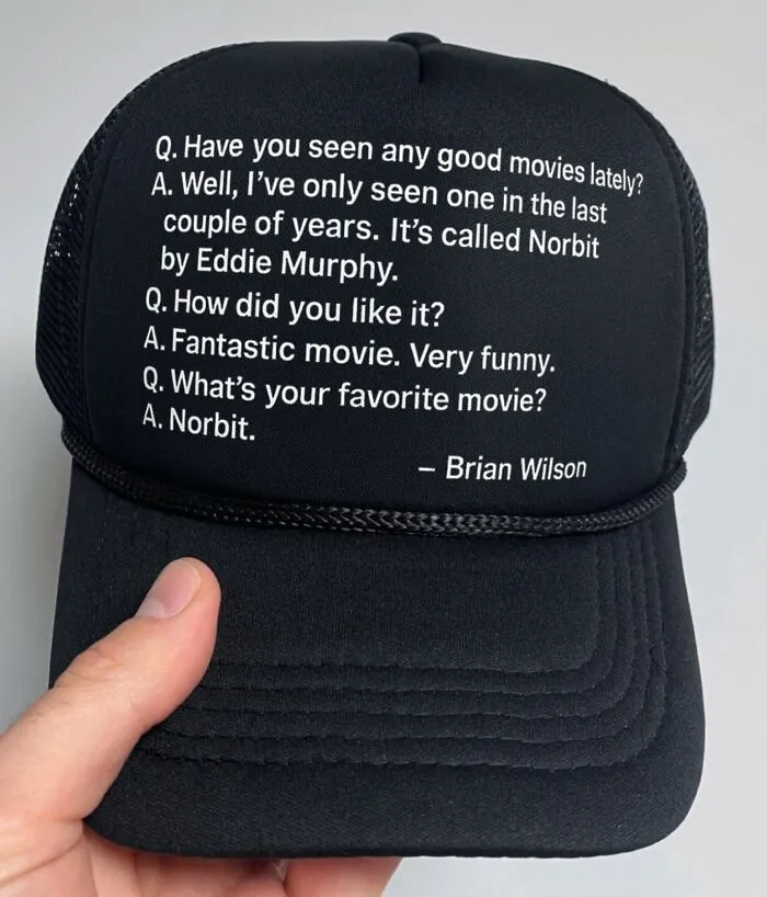 A black baseball hat printed with a hilarious interview text quote about the movie Norbit.